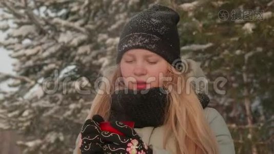女孩喜欢下雪。 一位针织的年轻女子在降雪期间在森林里喝茶。视频
