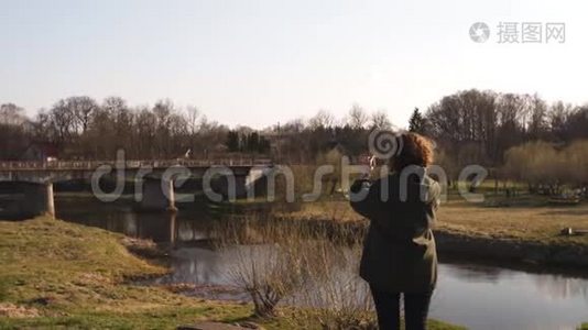 年轻女子在波罗的海国家城市萨比莱的背景下，用她的手机应用程序“河流”拍照视频