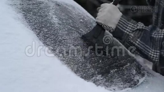 人用刷子擦车上的雪。 冬季暴风雪。 在降雪期间，人从汽车挡风玻璃上移除雪。 冬天下雪了视频