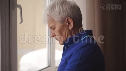 孤独的老人戴着眼镜站在窗边视频
