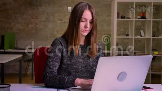红头发的女商人在电脑上打字，看着相机，把手指举起来显示类似的东西视频