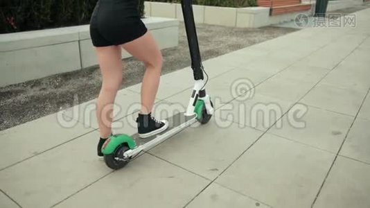 穿着黑色衣服和运动鞋的女孩，骑着电动滑板车在城市里转悠视频