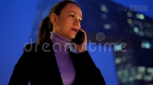 忙碌的女人用手机对着市中心的现代摩天大楼说话视频