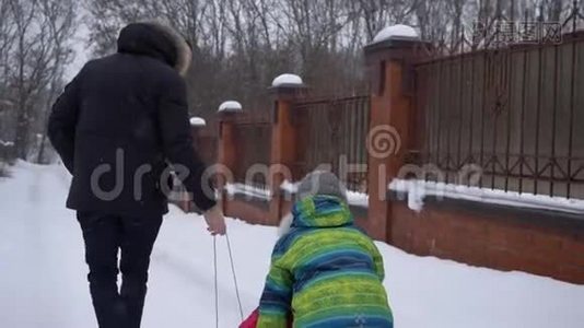 在冬天的周末下雪的时候，爸爸在街上橇着他的孩子们视频