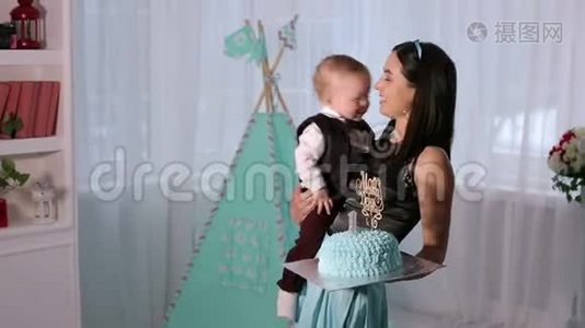 一个快乐的母亲和一个一岁的儿子在生日时带着蛋糕的肖像。视频
