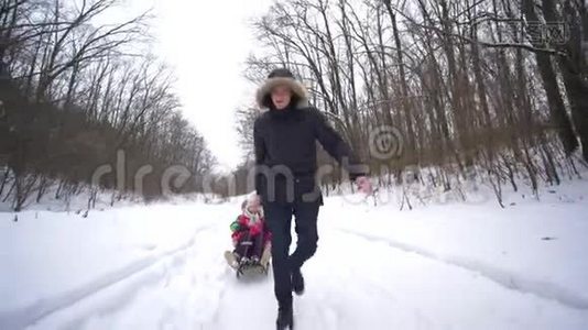 周末，年轻的父母带着雪橇和快乐的孩子在雪林视频