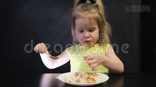 孩子们在黑桌上用勺子在黑色背景上吃煮熟的米饭和蘑菇视频