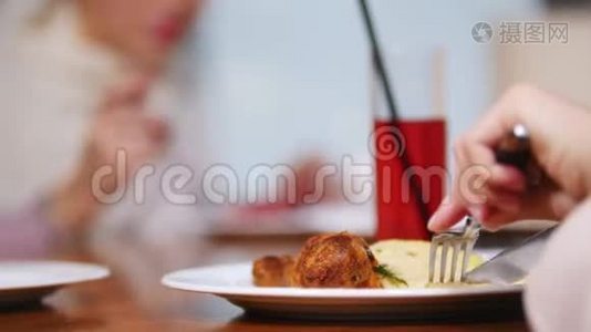 一位穆斯林妇女坐在餐馆吃这道菜。 用刀子割肉视频