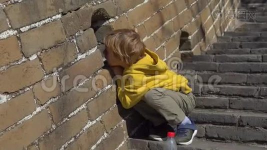 穿着黄色夹克的小男孩穿过中国长城的洞口视频