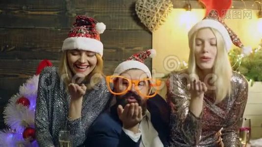 戴着大眼镜的长胡子男人和两个戴着`帽子的少女在新年的背景下用手掌吹糖果视频