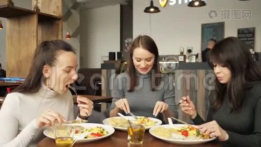 三个女朋友在咖啡馆里一起吃饭，聊天，享受他们的食物。视频