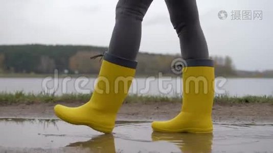 黄靴女子的腿在阴云的秋日穿过水坑视频