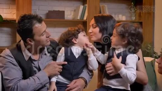 阿拉伯孩子双胞胎在客厅里坐在父母身上互相争斗。视频