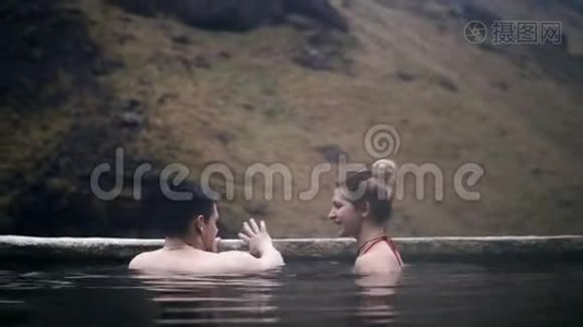 年轻夫妇在冰岛的温泉里放松。 游男女游山谷，浪漫约会..视频