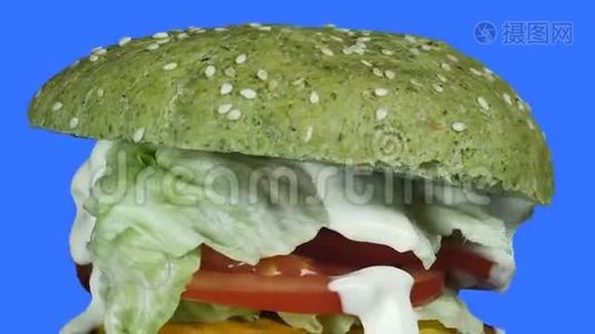 一架照相机`一个汉堡的自上而下的爆裂声中，有一个绿色的面包和一个绿色的西红柿和洋葱的馅饼在一个视频