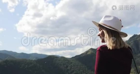 年轻女子徒步旅行者戴着帽子欣赏着山谷中令人惊叹的景色。视频