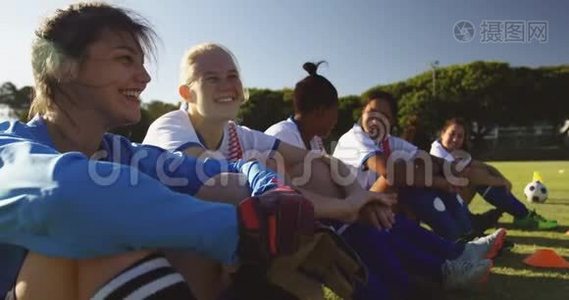 快乐多样的女足球员坐在足球场上交谈。 4k视频