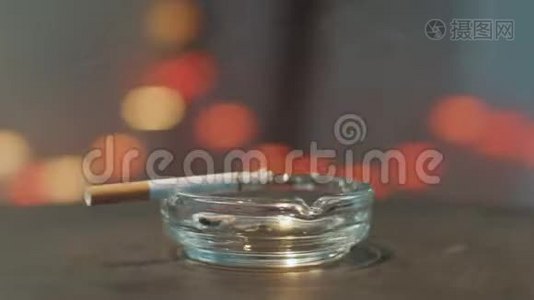 相机在玻璃烟灰缸周围旋转，边缘放着燃烧的香烟。视频