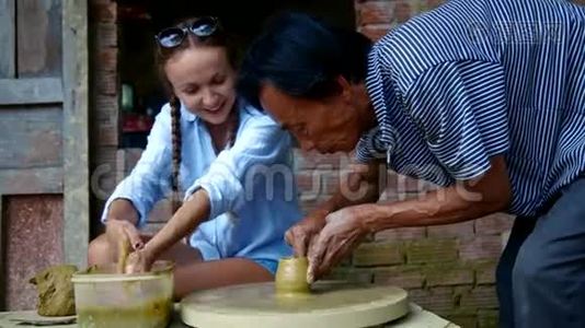 穿蓝色上衣的女人学着用轮子做陶罐视频