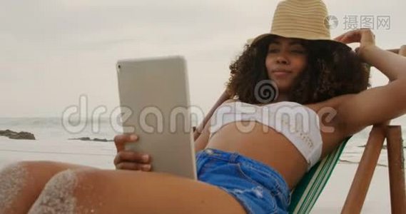 非洲裔美国妇女在海滩上使用数字平板电脑的正面景色视频