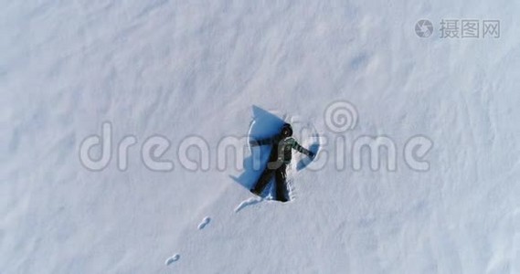 七岁的男孩做雪天使，空中镜头。 摄像机慢慢接近。视频