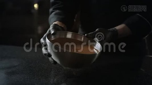 巧克力师把融化的巧克力从碗里倒入冷桌，用来调质，制作糖果和手工制作视频