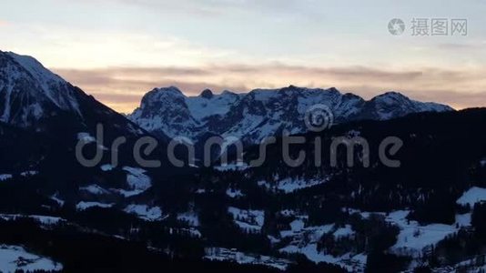 日落时分群山的空中镜头，积雪覆盖的山峰，4k视频