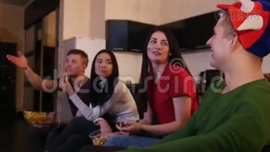 四个年轻人看足球比赛，吃垃圾食品，讨论比赛视频