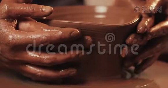 一对夫妇的手在陶工`的轮子上形成一壶粘土。 女性的手帮助男人`手塑造粘土的形状。 上景。视频