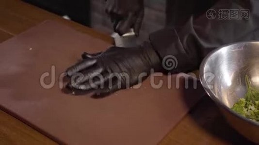 厨师双手戴黑色橡胶厨师手套，用刀刃在餐厅的切割板上压碎`部分视频