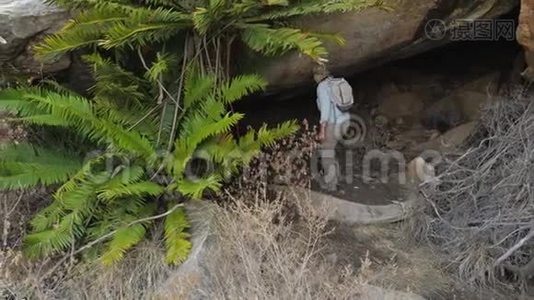 带背包攀登进入大石洞的女游客视频