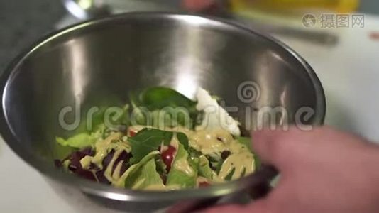 厨师手拿着大铝碗和沙拉倒入酱汁。 把番茄、菠菜、菜、莴苣混合在一起视频