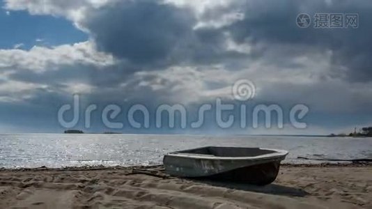 渔船躺在湖边的沙滩上，云彩划过天空。周围没有人。视频