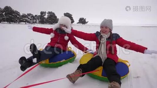 快乐的孩子在雪的路上骑雪，快乐地笑。 女孩们在冬天雪橇，微笑着。 快乐视频