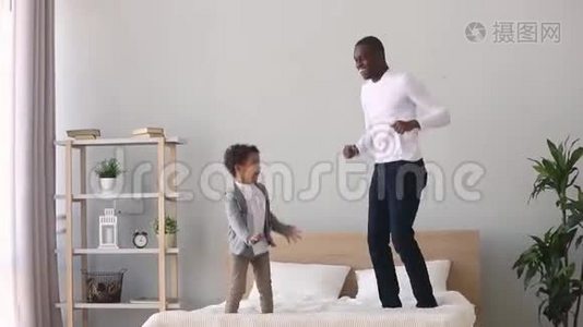 快乐无忧无虑的非洲父亲和儿子在床上跳跃视频