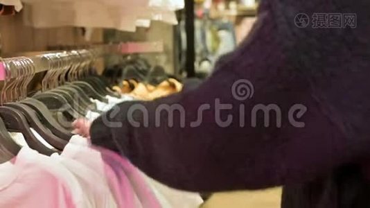 女孩的特写镜头`她的手在商店里挑选挂在衣架上的衣服出售视频