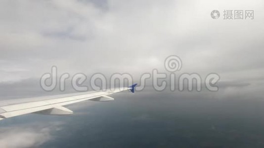 飞机的一个大翅膀解剖了天空中薄薄的云层，游客的飞行视频