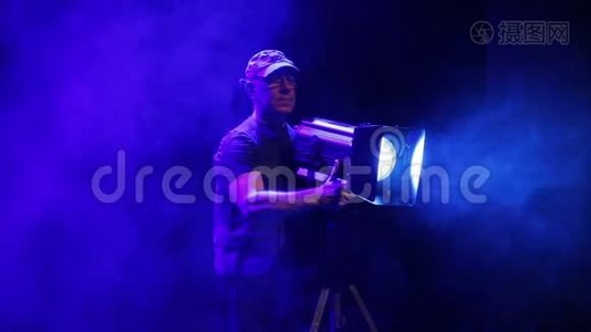 舞台上的一个人用一台戏剧放映机拍摄烟雾中的光线视频