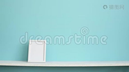 现代客房装饰与相框模型。 白色的架子，贴在青绿色的墙上，用手放下蜘蛛植物视频