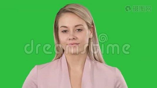 年轻美丽的女士穿着粉红色，看着相机，想着在绿色屏幕上微微微笑的东西，Chroma键。视频