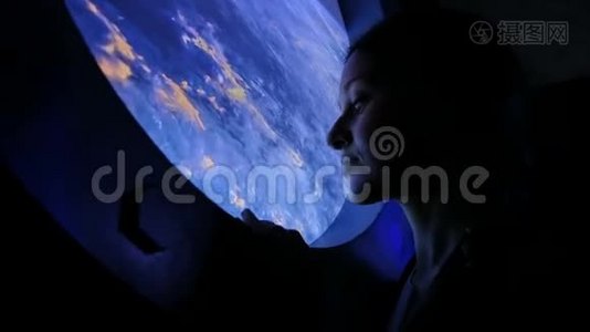 女孩在太空的舷窗里看视频