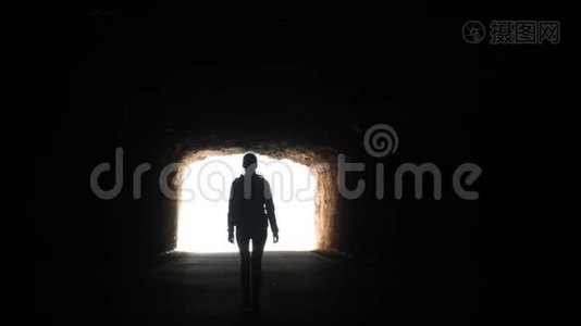 镜头跟随一个女人的剪影穿过黑暗的隧道，走向空中举起的手臂。视频