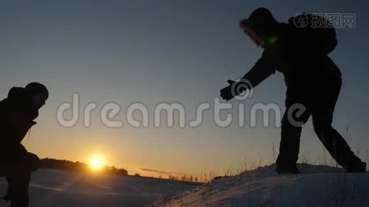 登山者帮助朋友攀爬伸出援助之手。 山顶上有两名游客。 冬天旅行者的剪影视频