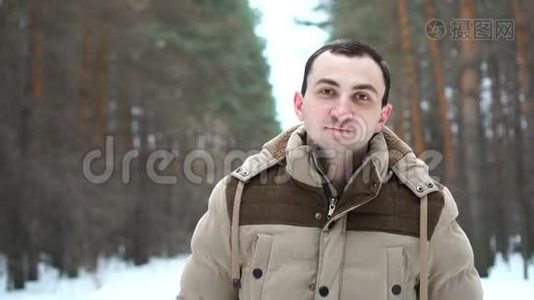 森林里穿夹克的微笑男人的肖像。 人站在冬林中..视频