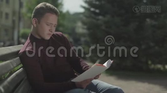 年轻人合上一本书，从长凳上站起来视频