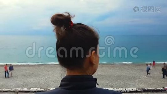 年轻女性悲伤地看着海滨海滩上的人，忧郁，自由视频