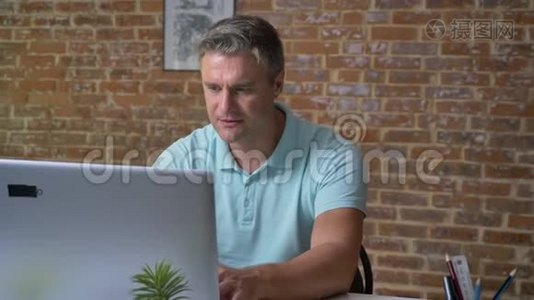 一个成熟的白人商人在他的笔记本电脑上打字后，用拳头展示他的胜利姿态视频