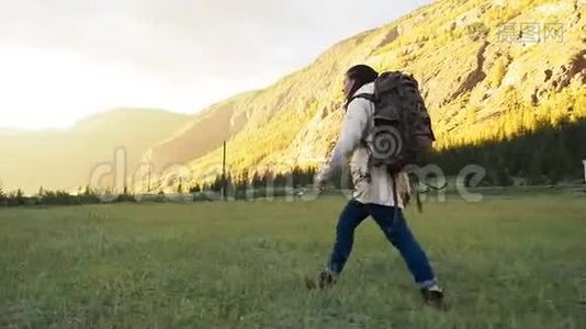 徒步旅行者背包族女孩走在绿色的田野上视频