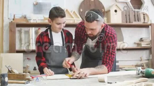 爸爸正在帮儿子用尺子在木板上刻线视频