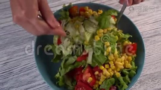 一个女人用西红柿、草药和玉米搅拌两个叉子、一份蔬菜沙拉视频